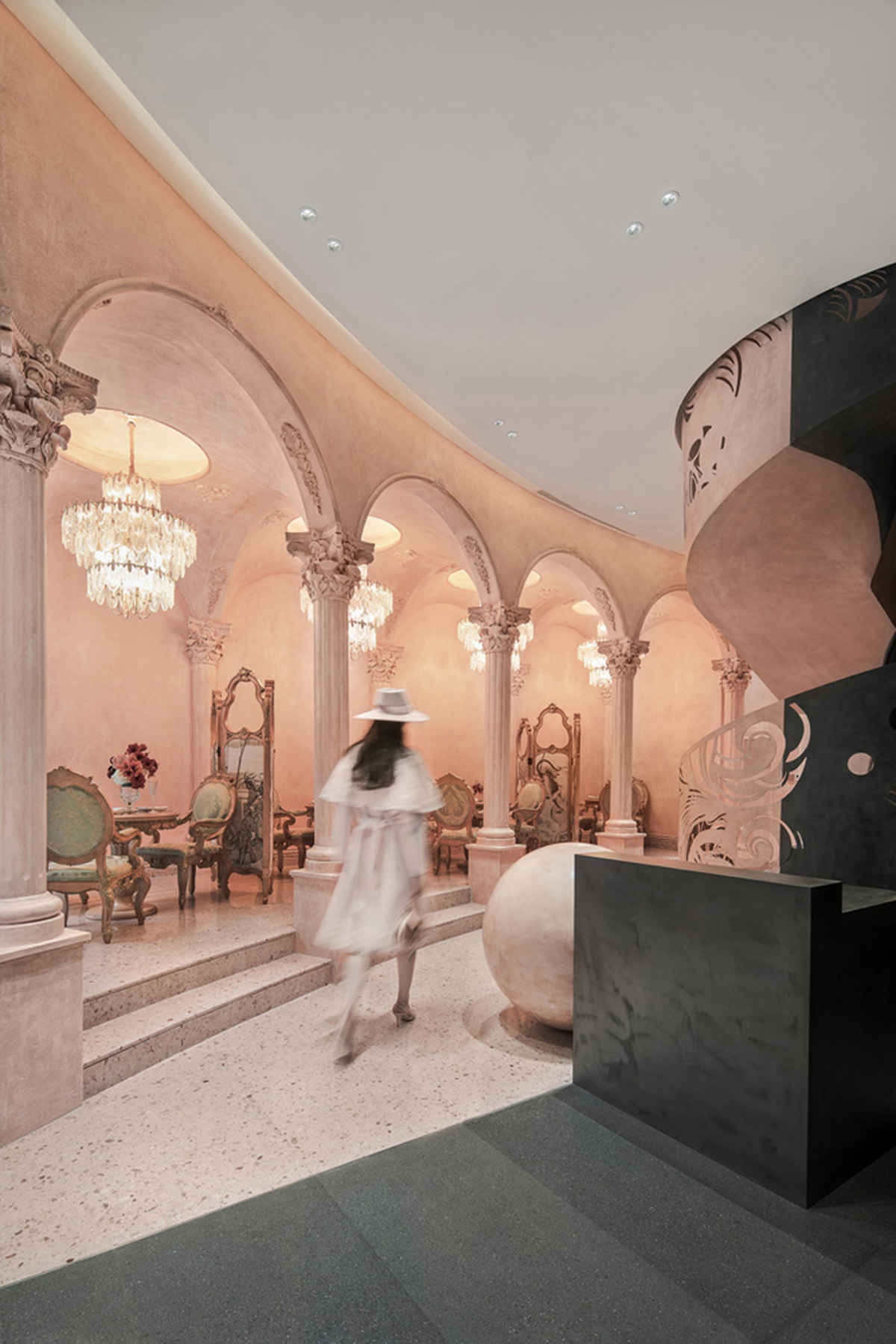 Pink elements and dark colors create sharp contrast in the interiors of restaurant and showroom