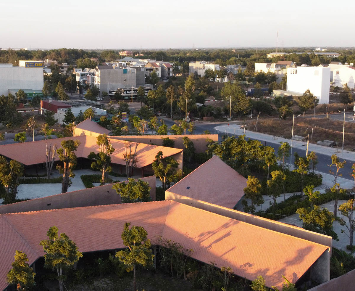 TAA DESIGN built public space with pitched roofs and rough concrete walls painted with pink tones