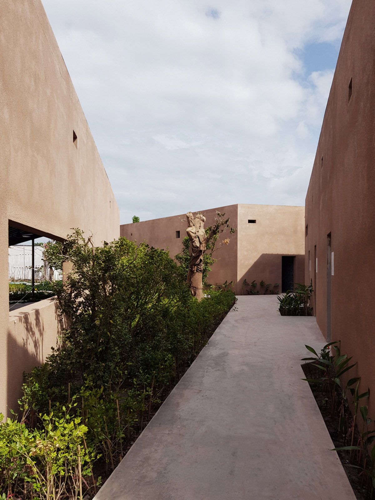 TAA DESIGN built public space with pitched roofs and rough concrete walls painted with pink tones