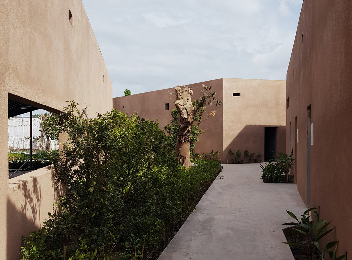 TAA DESIGN built public space with pitched roofs and rough concrete walls painted with pink tones