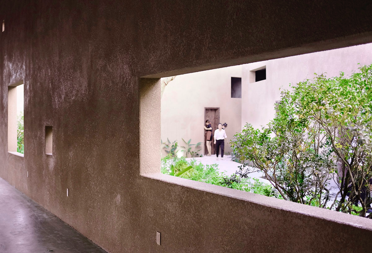 TAA DESIGN built public space with pitched roofs and rough concrete walls painted with pink tones