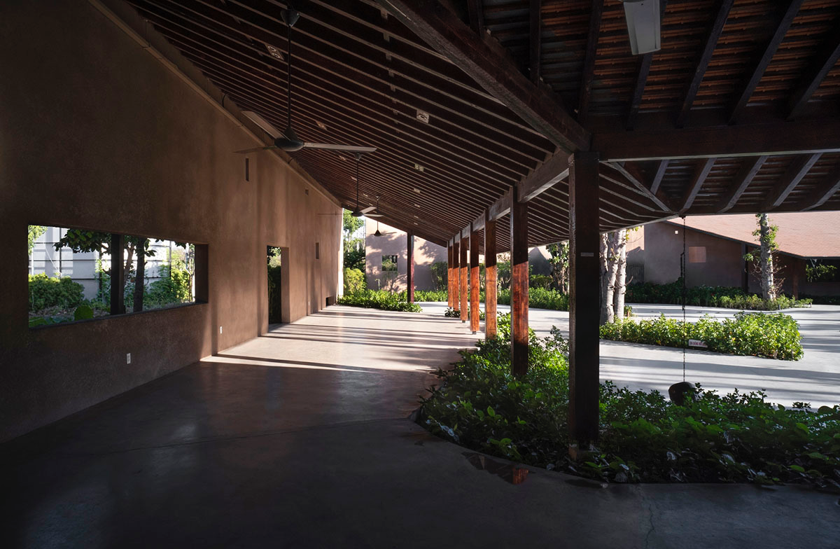 TAA DESIGN built public space with pitched roofs and rough concrete walls painted with pink tones