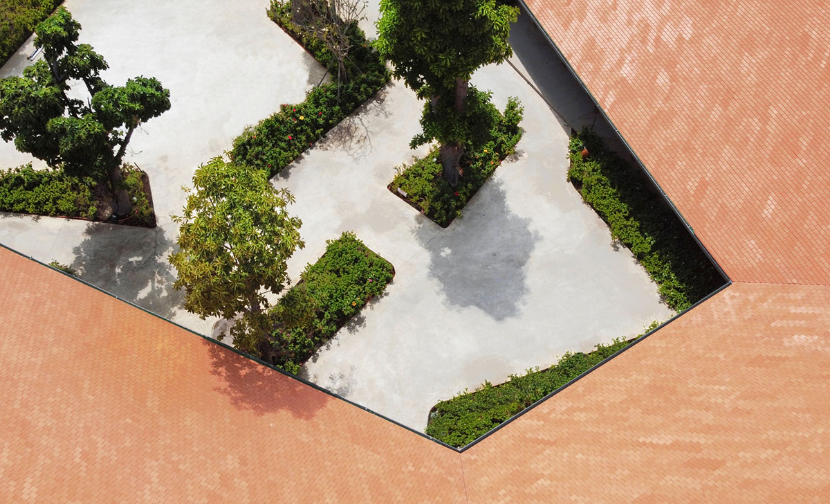 TAA DESIGN built public space with pitched roofs and rough concrete walls painted with pink tones