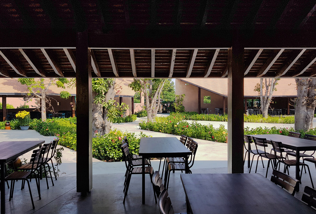 TAA DESIGN built public space with pitched roofs and rough concrete walls painted with pink tones