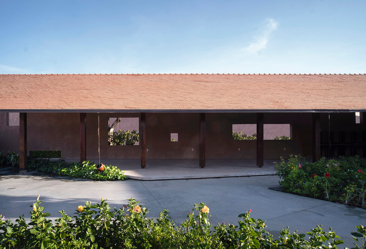 TAA DESIGN built public space with pitched roofs and rough concrete walls painted with pink tones