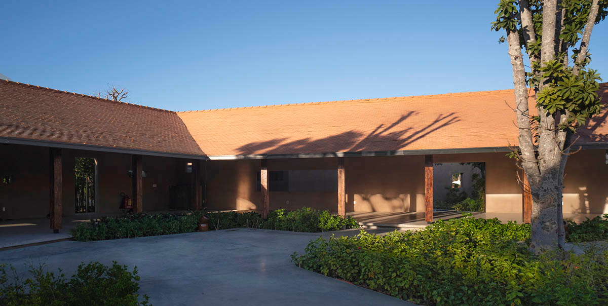 TAA DESIGN built public space with pitched roofs and rough concrete walls painted with pink tones