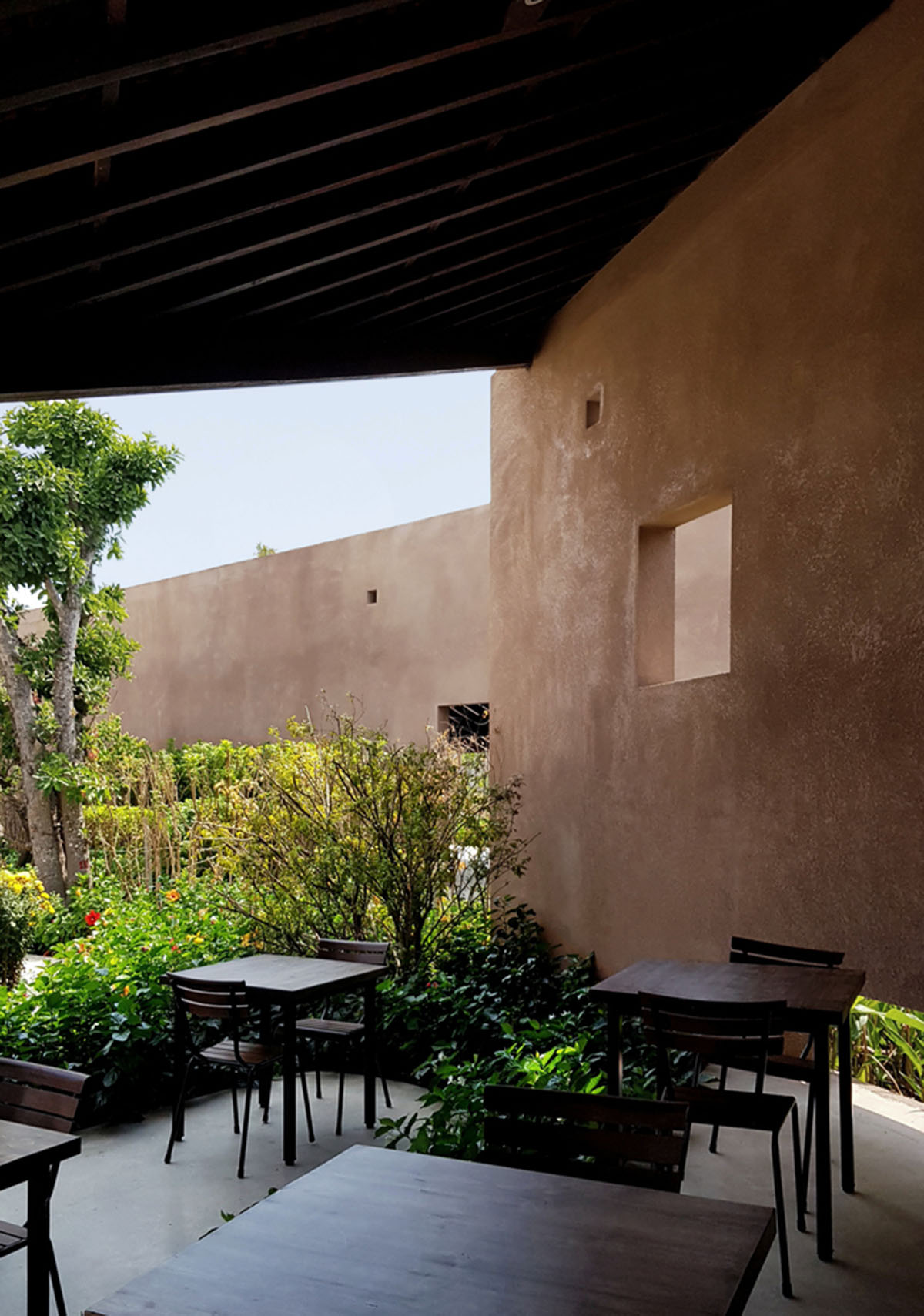 TAA DESIGN built public space with pitched roofs and rough concrete walls painted with pink tones