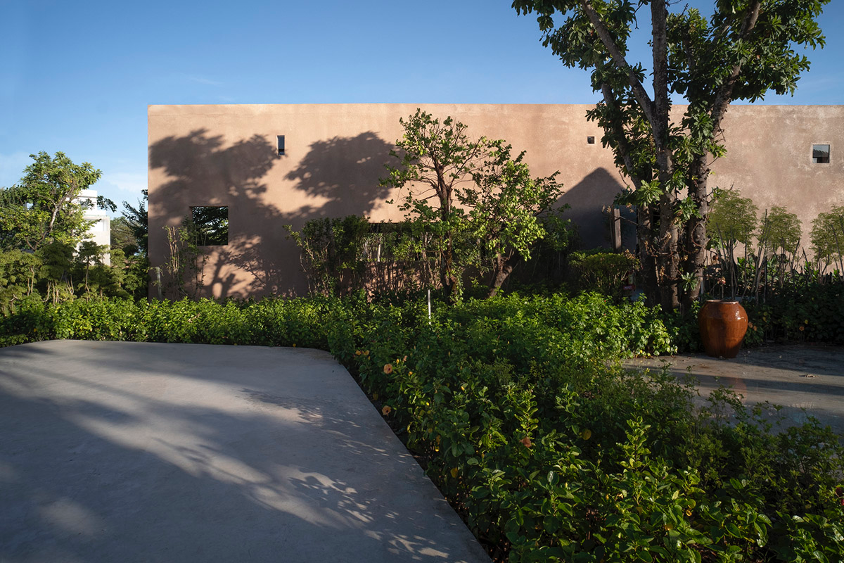TAA DESIGN built public space with pitched roofs and rough concrete walls painted with pink tones