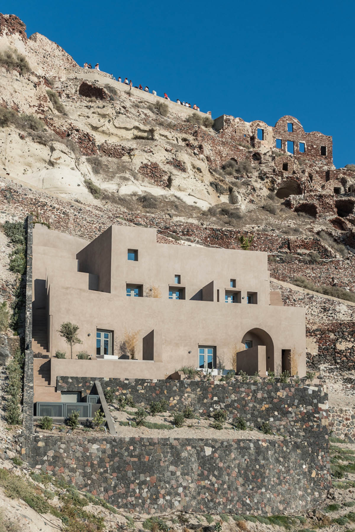 Kapsimalis Architects built castle-like hotel almost disappearing it on a steep hillside of Oia