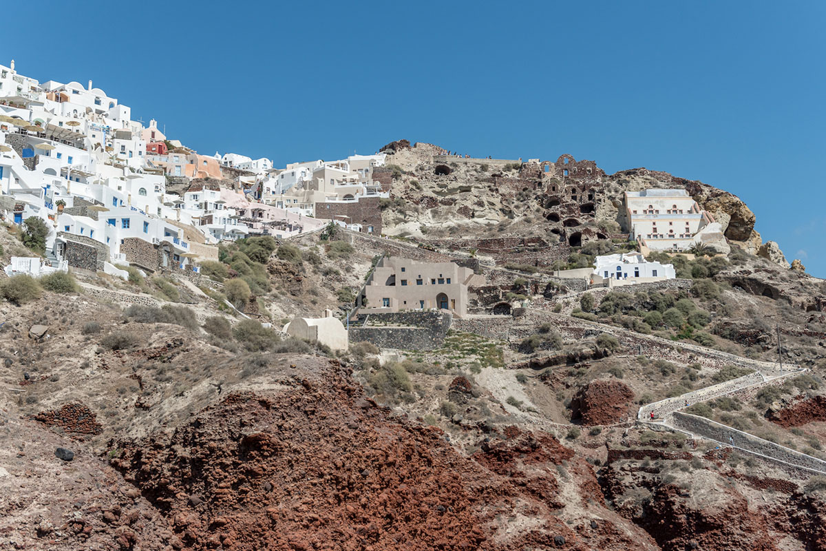 Kapsimalis Architects built castle-like hotel almost disappearing it on a steep hillside of Oia