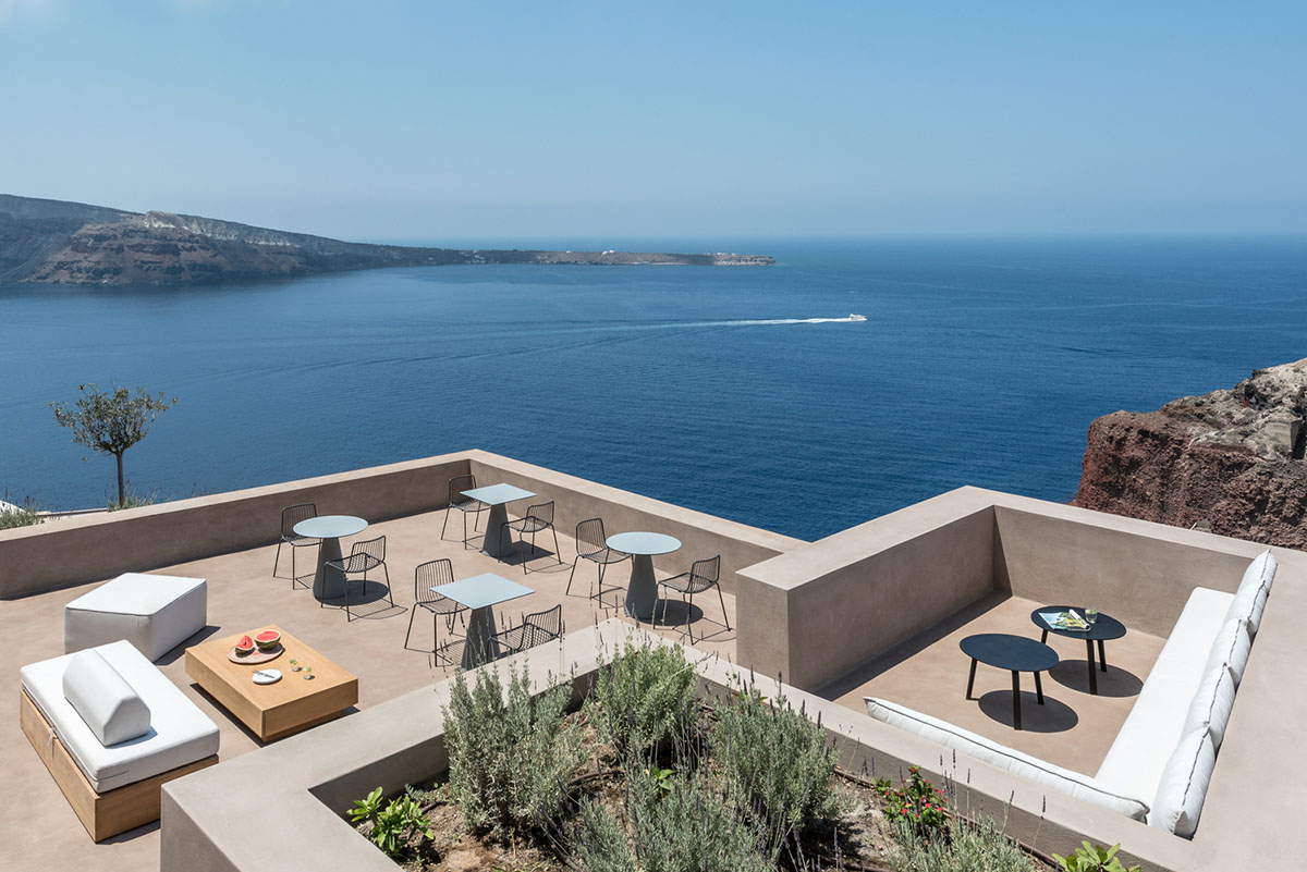 Kapsimalis Architects built castle-like hotel almost disappearing it on a steep hillside of Oia