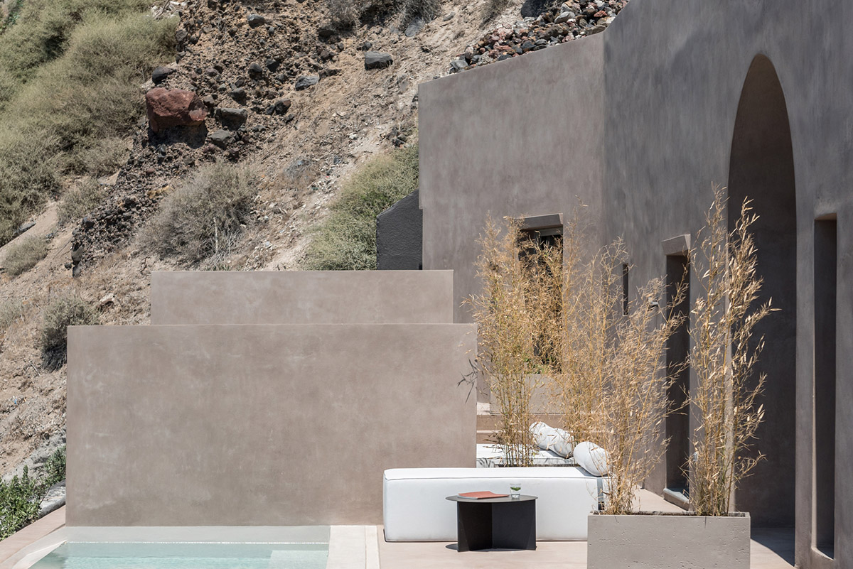 Kapsimalis Architects built castle-like hotel almost disappearing it on a steep hillside of Oia