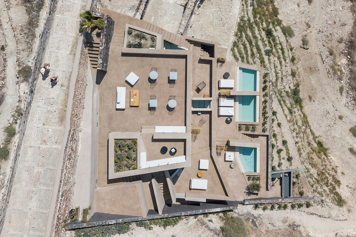 Kapsimalis Architects built castle-like hotel almost disappearing it on a steep hillside of Oia