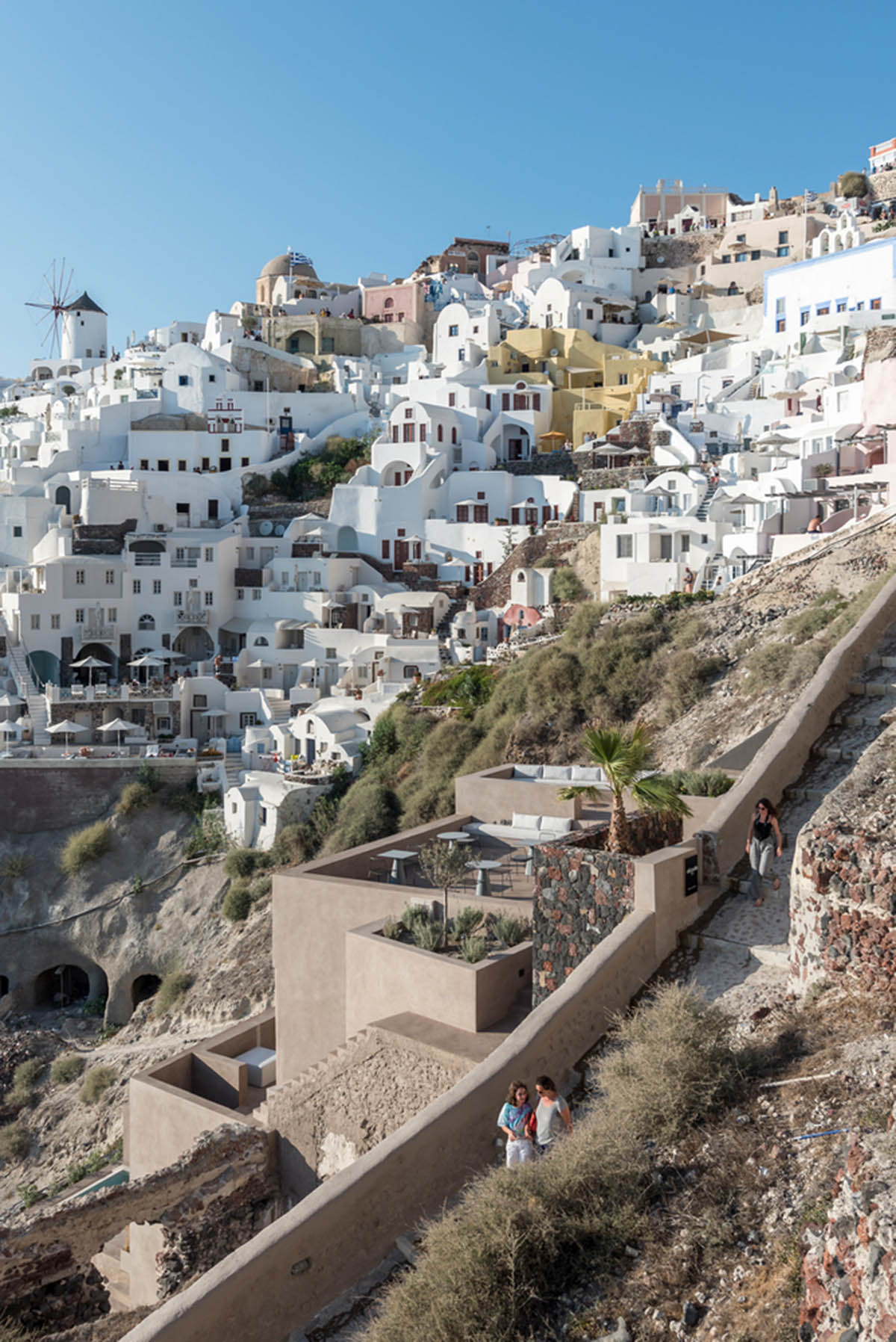 Kapsimalis Architects built castle-like hotel almost disappearing it on a steep hillside of Oia