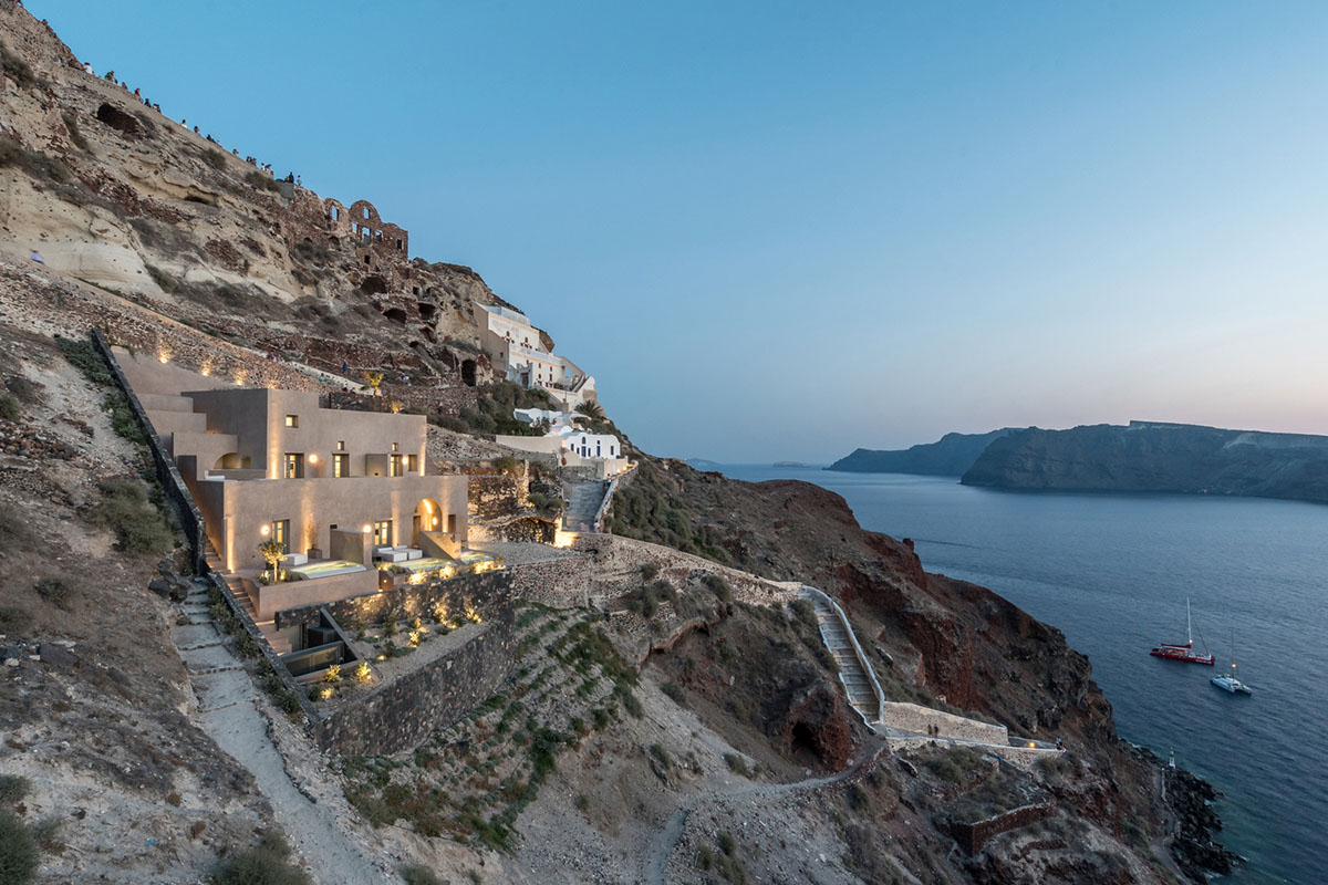 Kapsimalis Architects built castle-like hotel almost disappearing it on a steep hillside of Oia