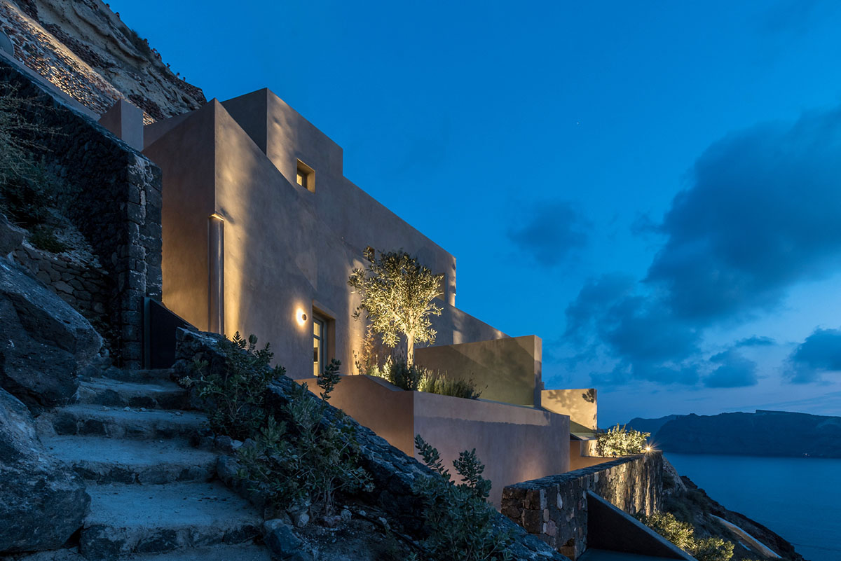 Kapsimalis Architects built castle-like hotel almost disappearing it on a steep hillside of Oia
