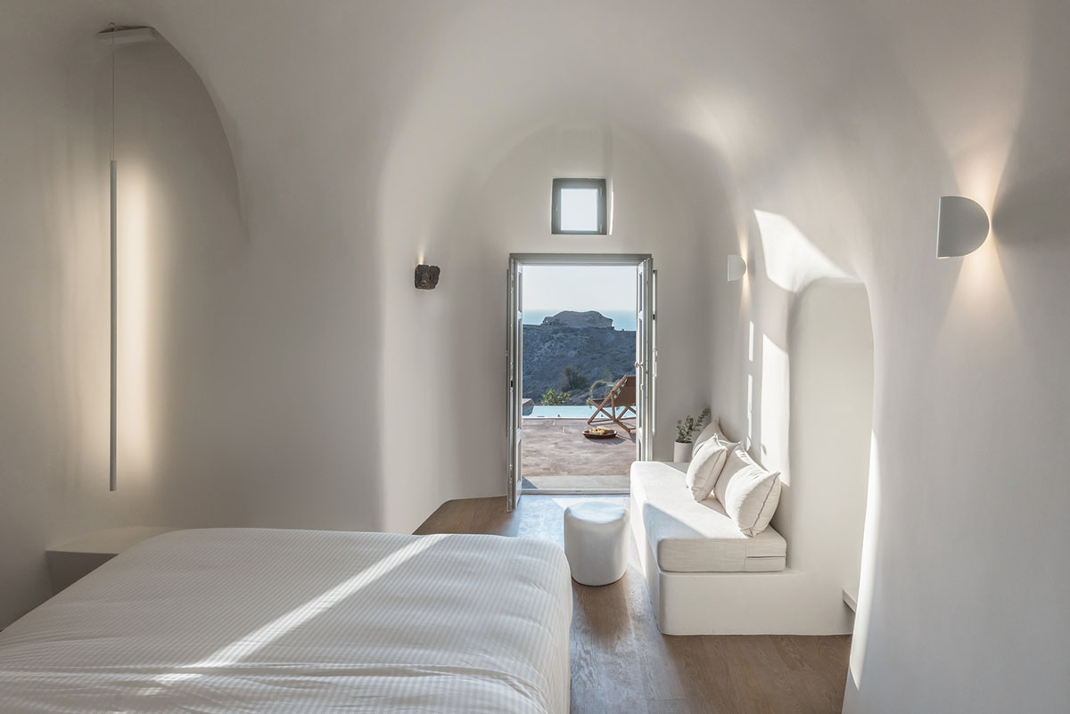 Kapsimalis Architects built castle-like hotel almost disappearing it on a steep hillside of Oia
