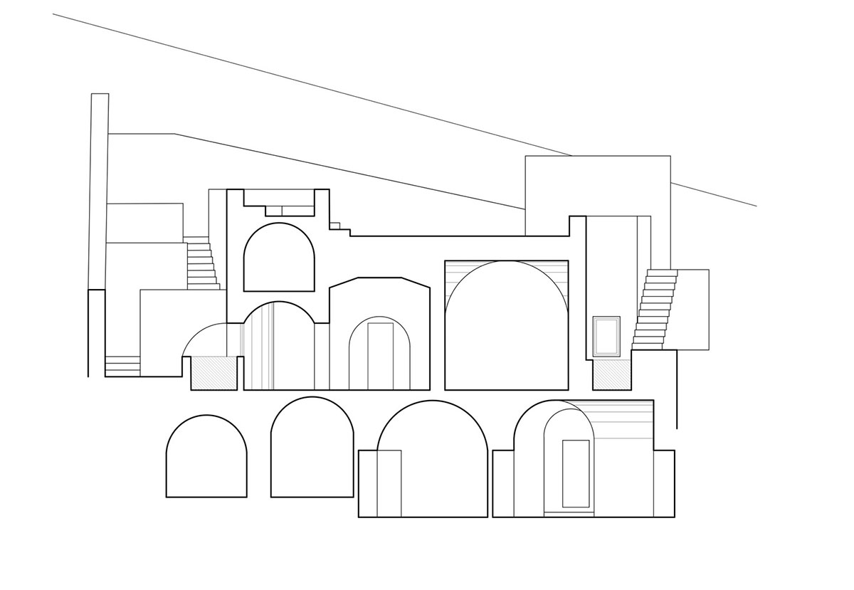 Kapsimalis Architects built castle-like hotel almost disappearing it on a steep hillside of Oia