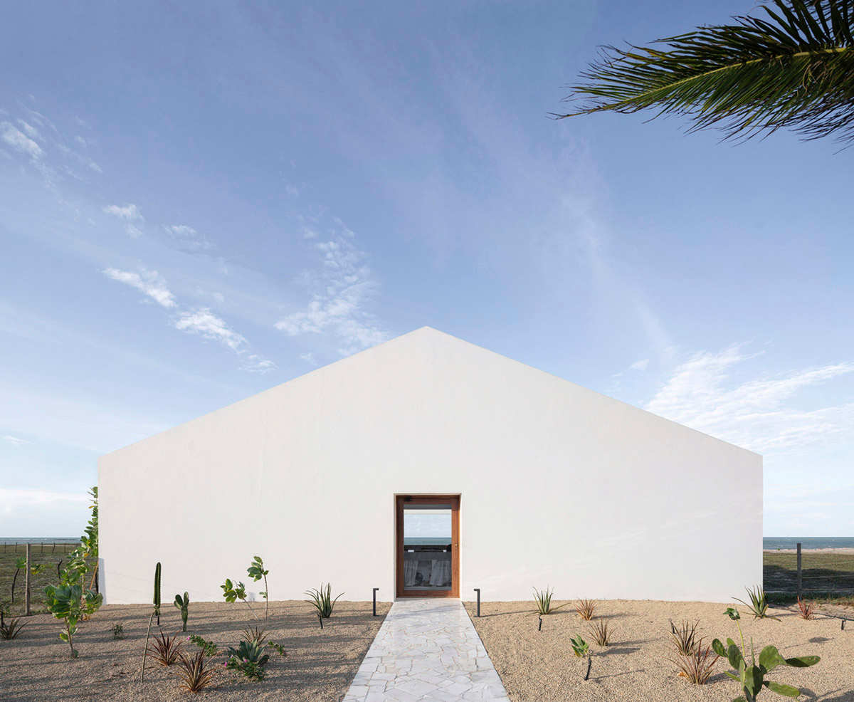 Two identical all-white volumes form this house by Atelier Branco Arquitetura on a flat landscape