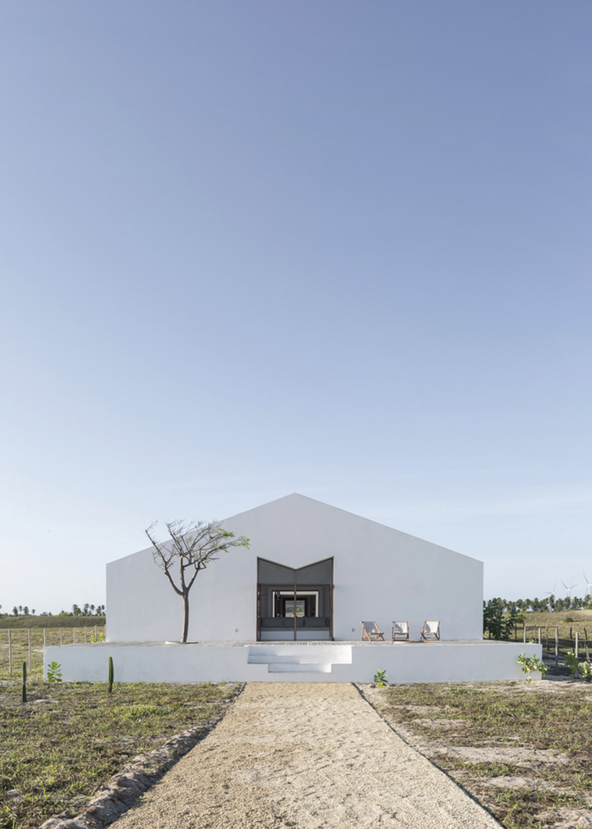 Two identical all-white volumes form this house by Atelier Branco Arquitetura on a flat landscape