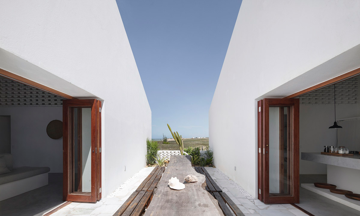 Two identical all-white volumes form this house by Atelier Branco Arquitetura on a flat landscape