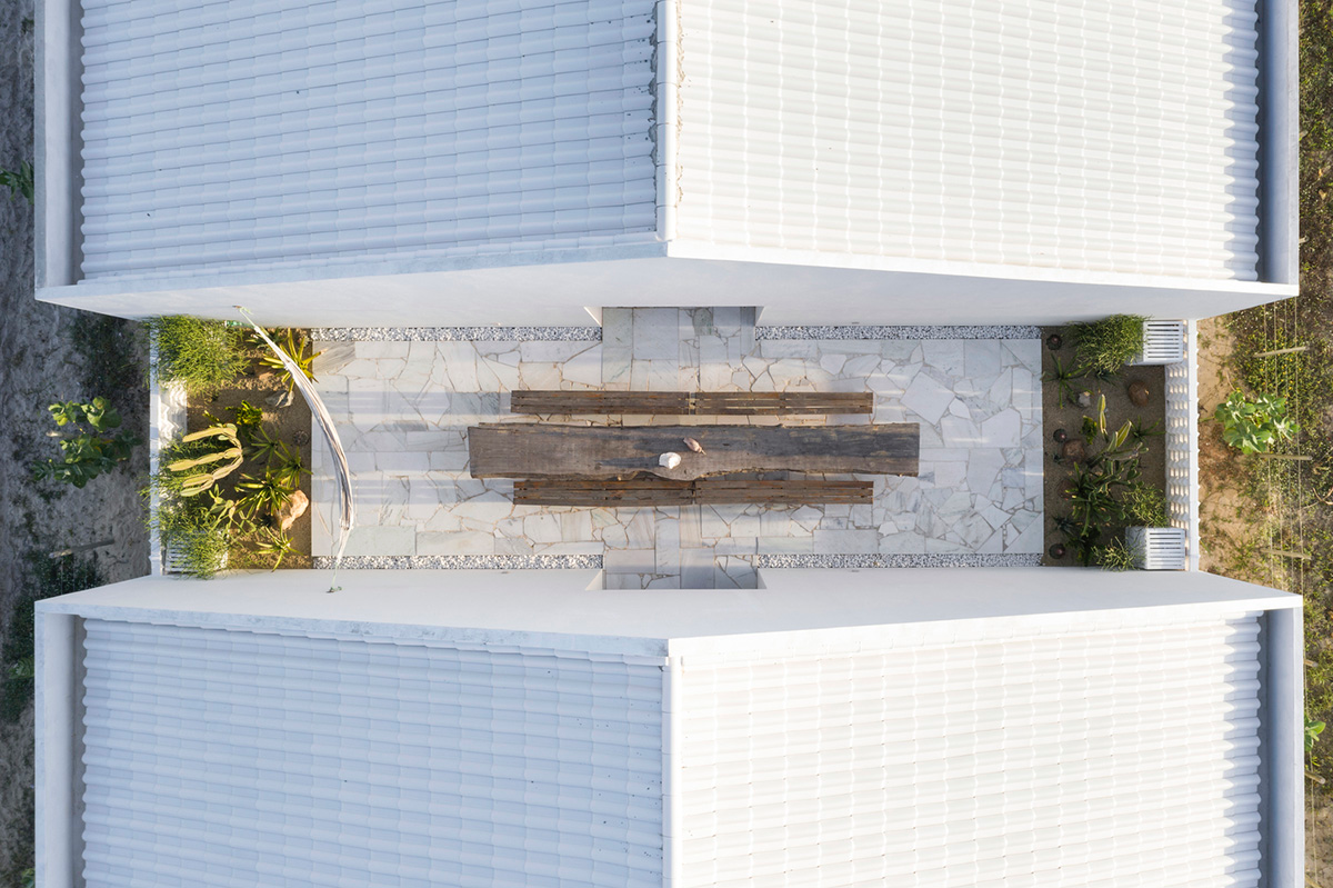 Two identical all-white volumes form this house by Atelier Branco Arquitetura on a flat landscape