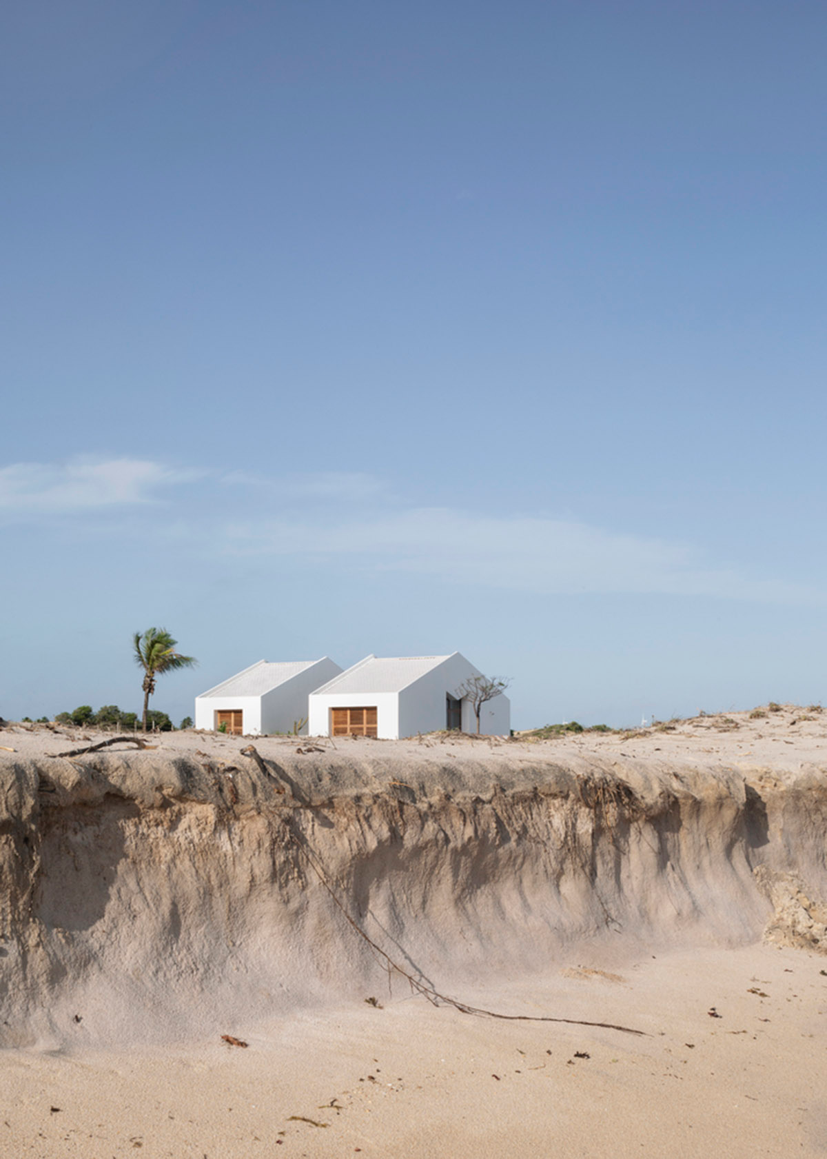 Two identical all-white volumes form this house by Atelier Branco Arquitetura on a flat landscape