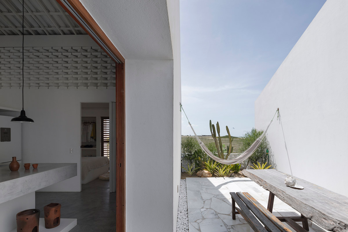 Two identical all-white volumes form this house by Atelier Branco Arquitetura on a flat landscape