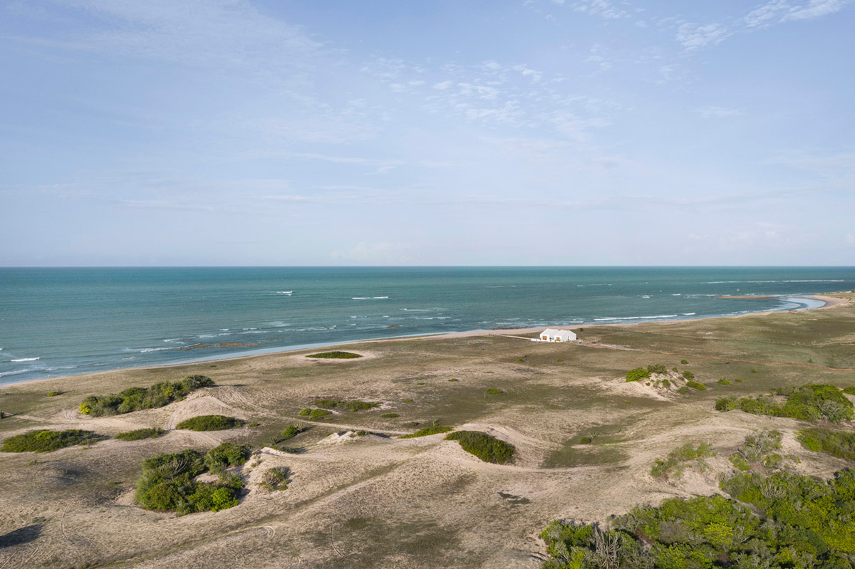 Two identical all-white volumes form this house by Atelier Branco Arquitetura on a flat landscape