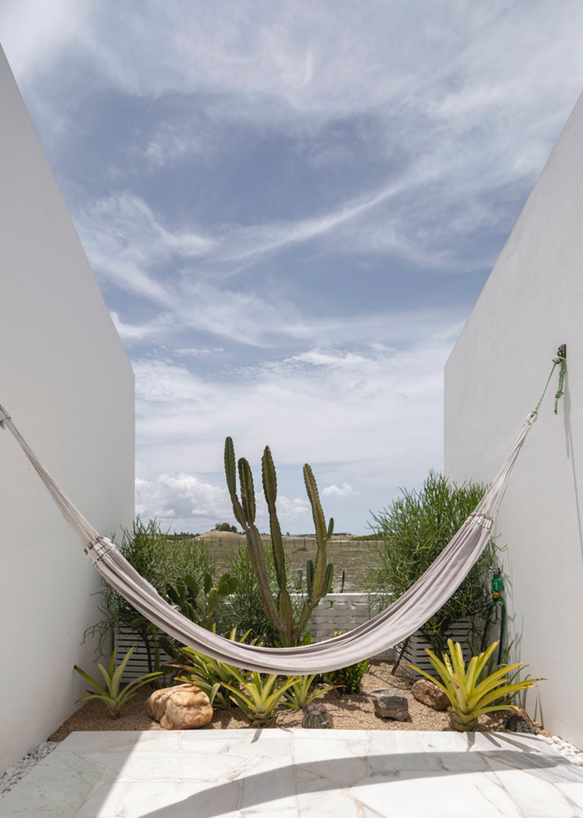 Two identical all-white volumes form this house by Atelier Branco Arquitetura on a flat landscape