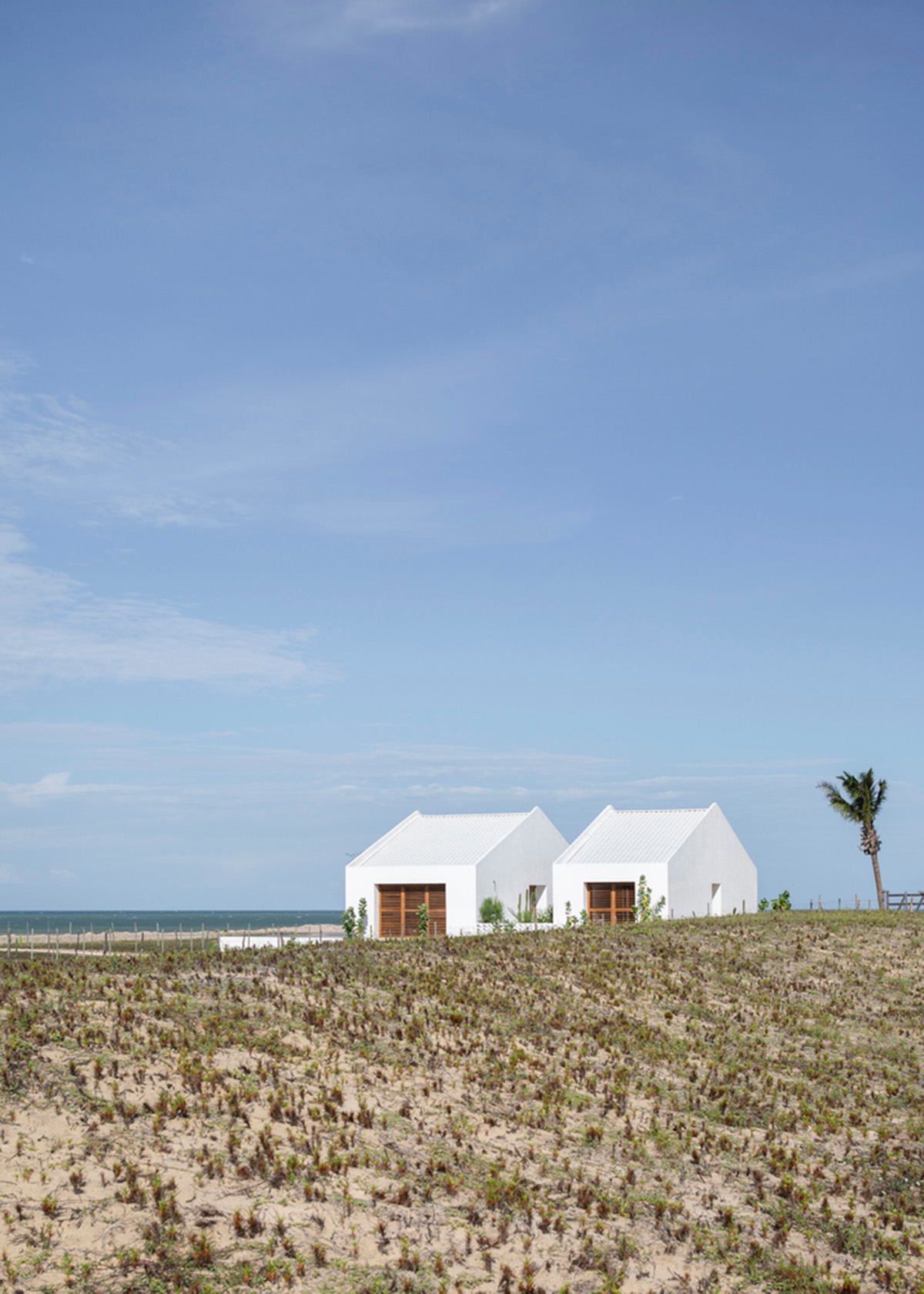 Two identical all-white volumes form this house by Atelier Branco Arquitetura on a flat landscape