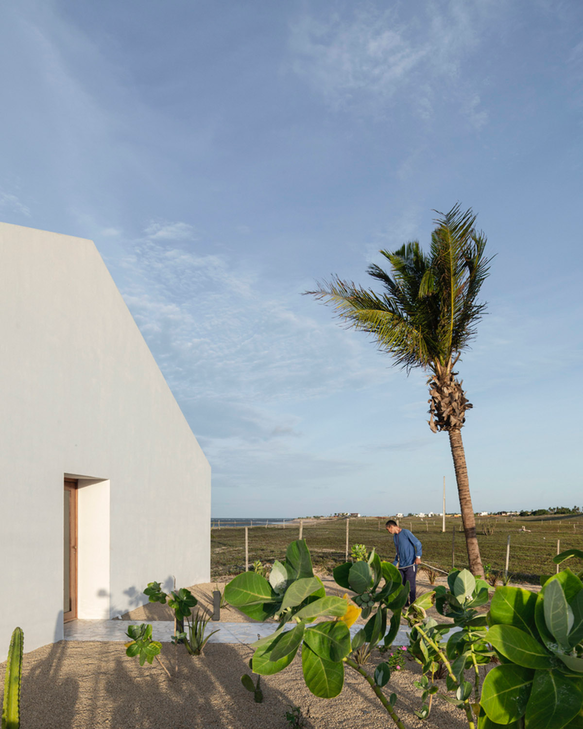 Two identical all-white volumes form this house by Atelier Branco Arquitetura on a flat landscape