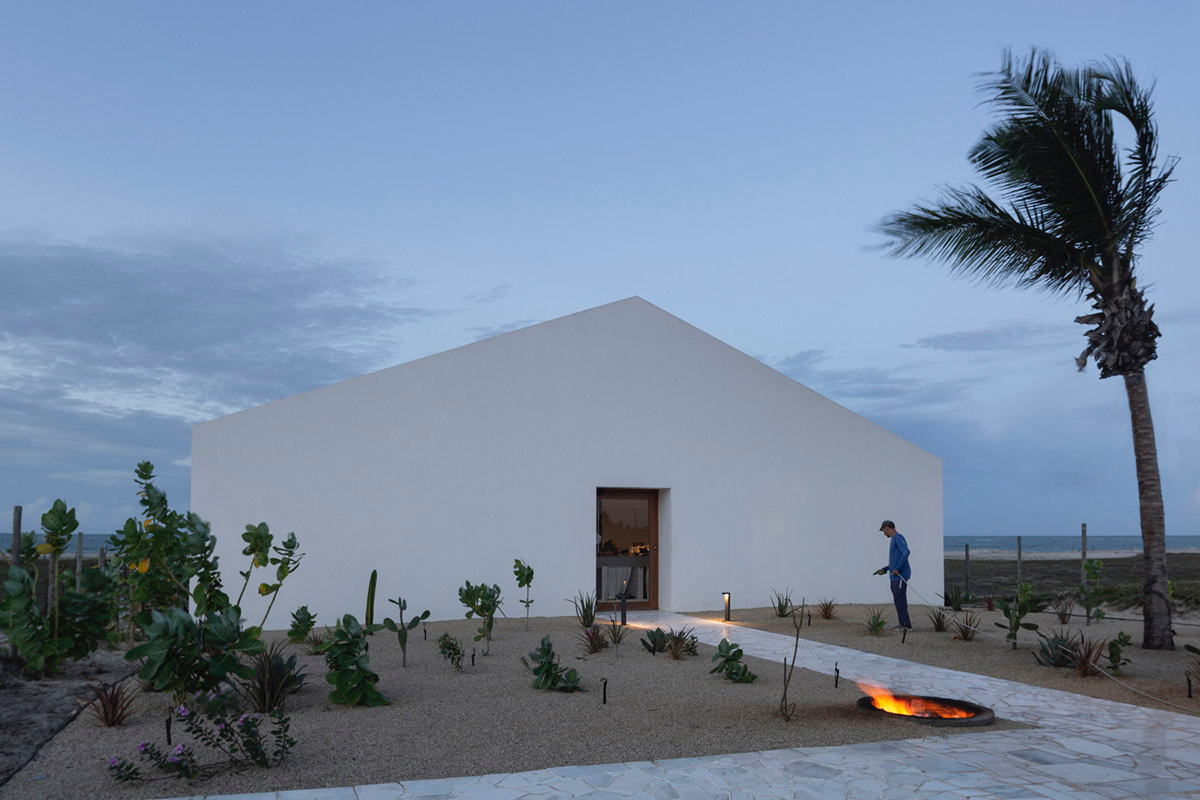 Two identical all-white volumes form this house by Atelier Branco Arquitetura on a flat landscape