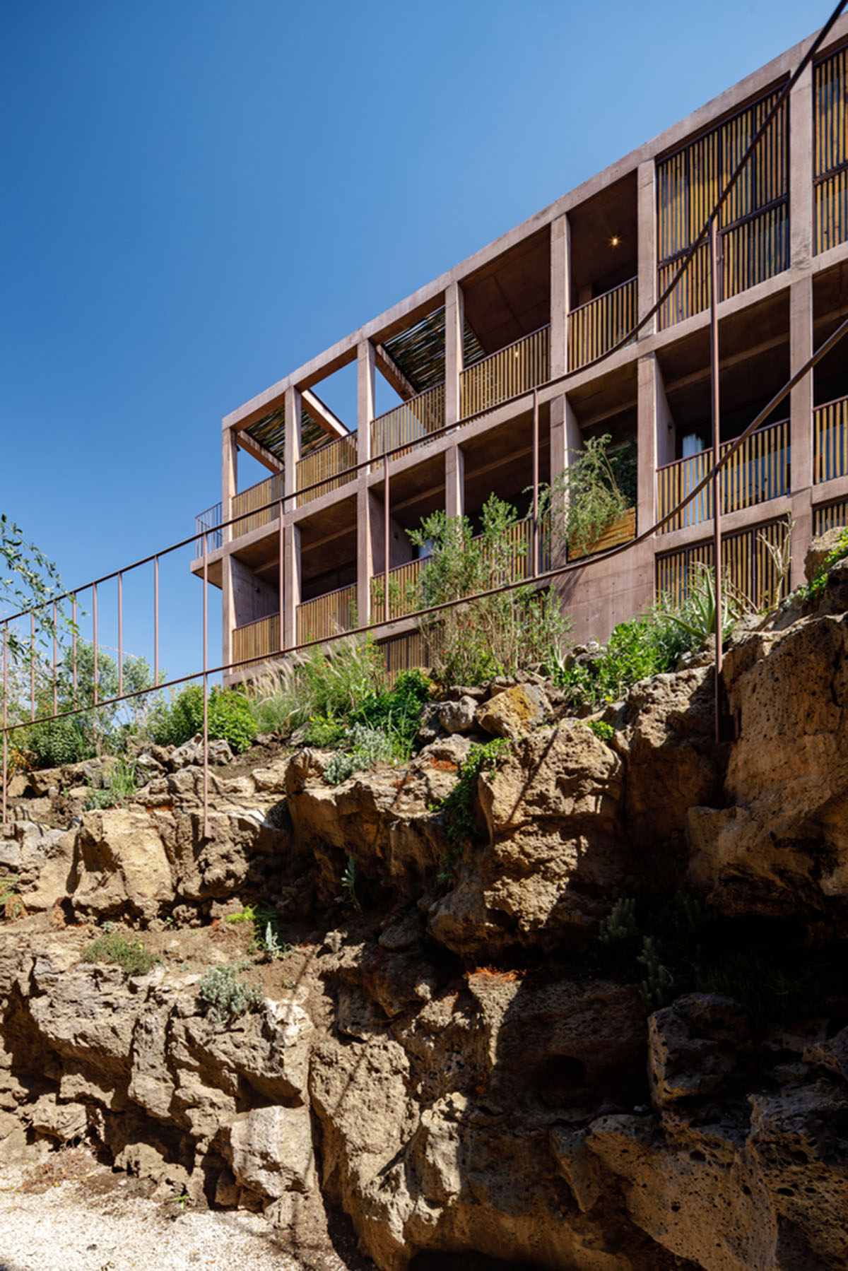 This gridded hotel made from pigmented concrete and volcanic stone sits on rugged terrain in Mexico