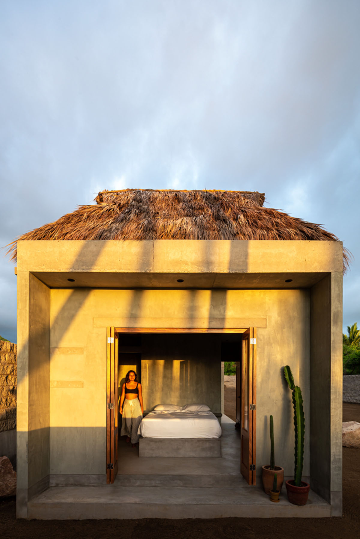 PALMA's small bungalow combines two functions with thatched roofs and a central patio in Mexico
