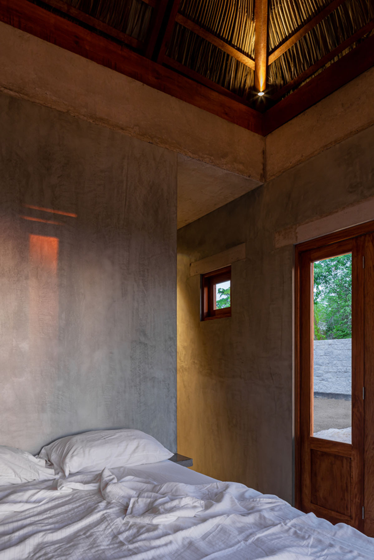 PALMA's small bungalow combines two functions with thatched roofs and a central patio in Mexico