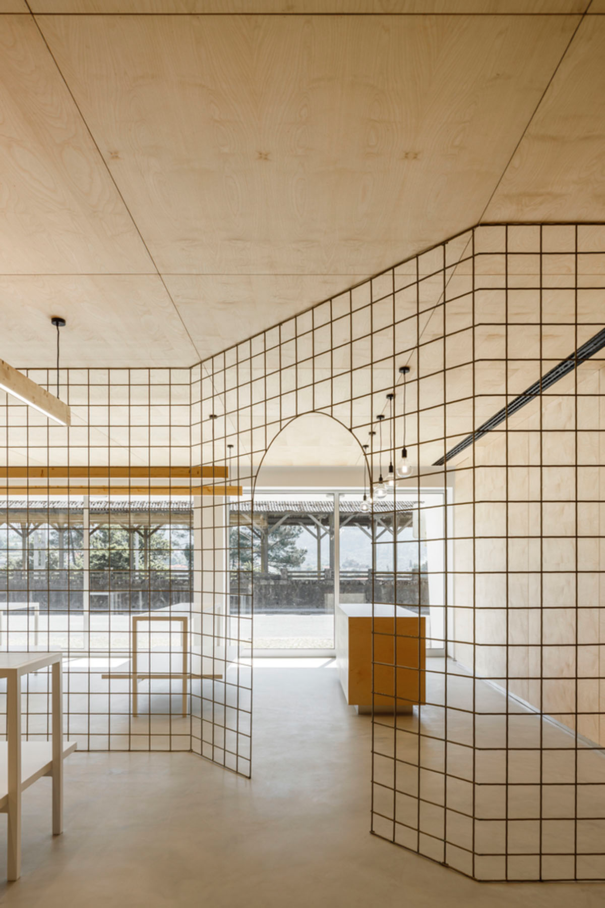 stu.dere divides interior space with golden wire meshes for multiple uses in this store in Portugal