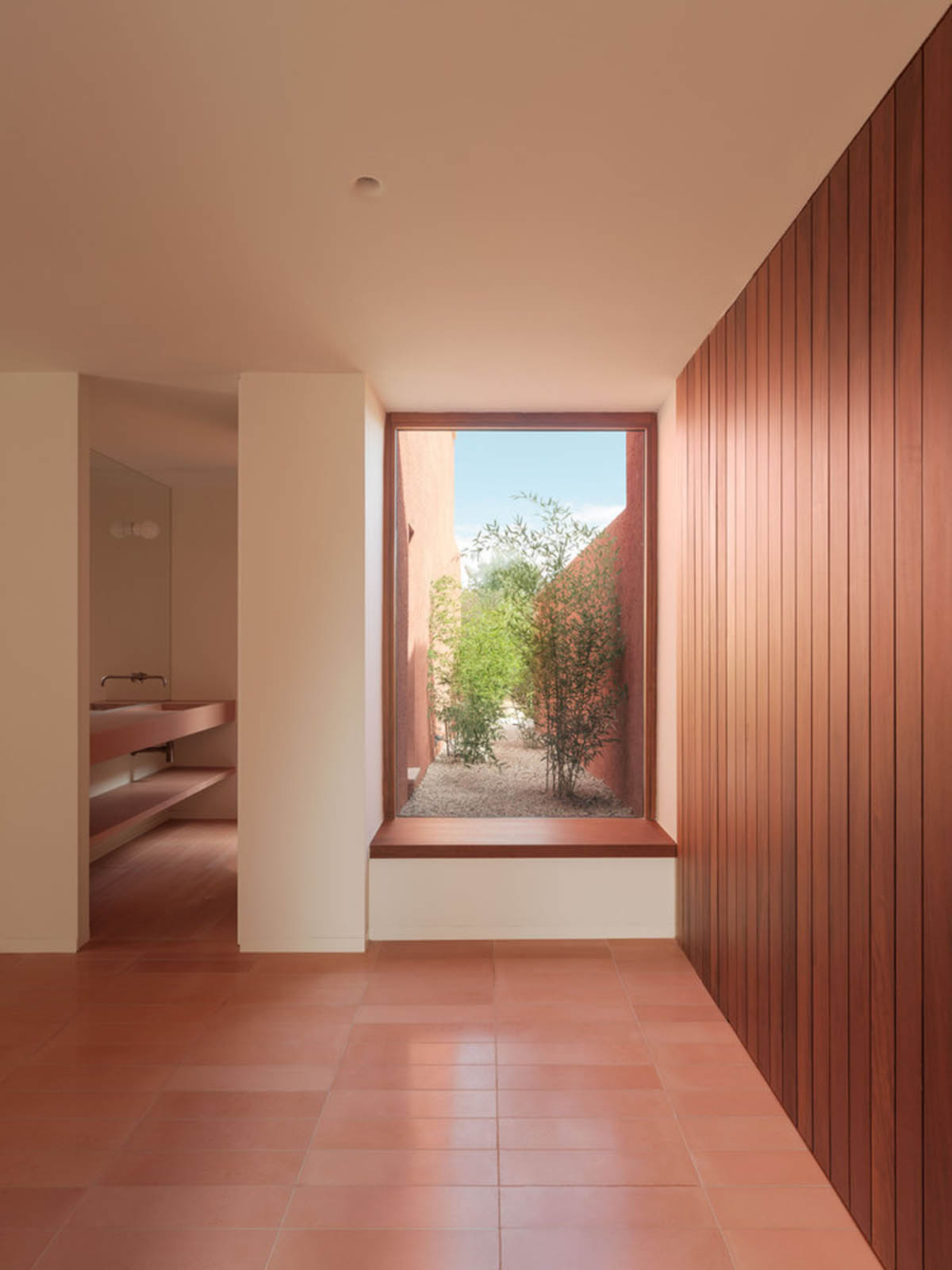 Large openings and reddish-colored façades mark this holiday home by Isla Architects in a rustic land