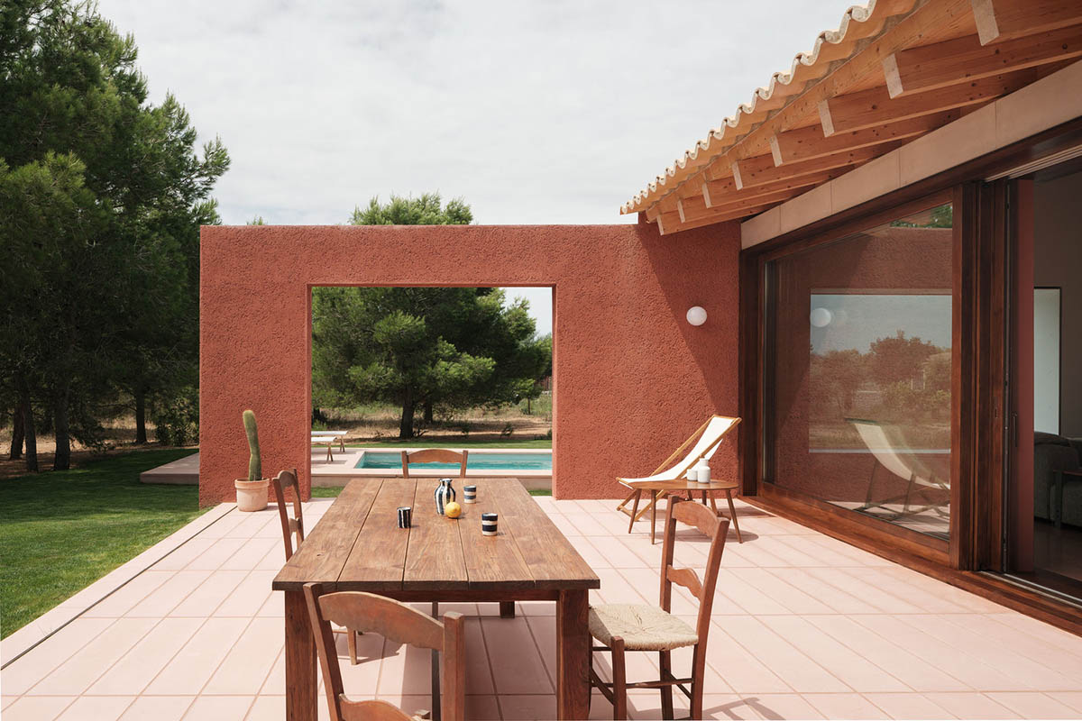 Large openings and reddish-colored façades mark this holiday home by Isla Architects in a rustic land