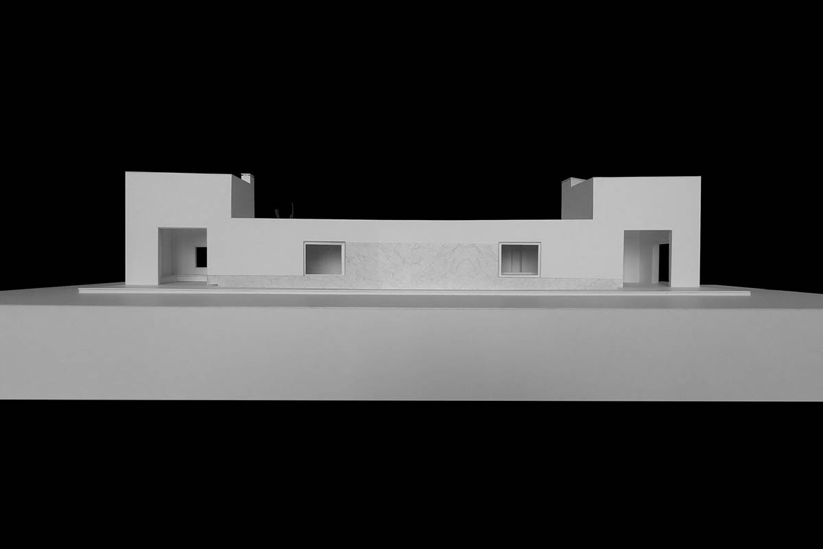 Castle-like red-pigmented house features recessed volumes on arid landscape of Alentejo