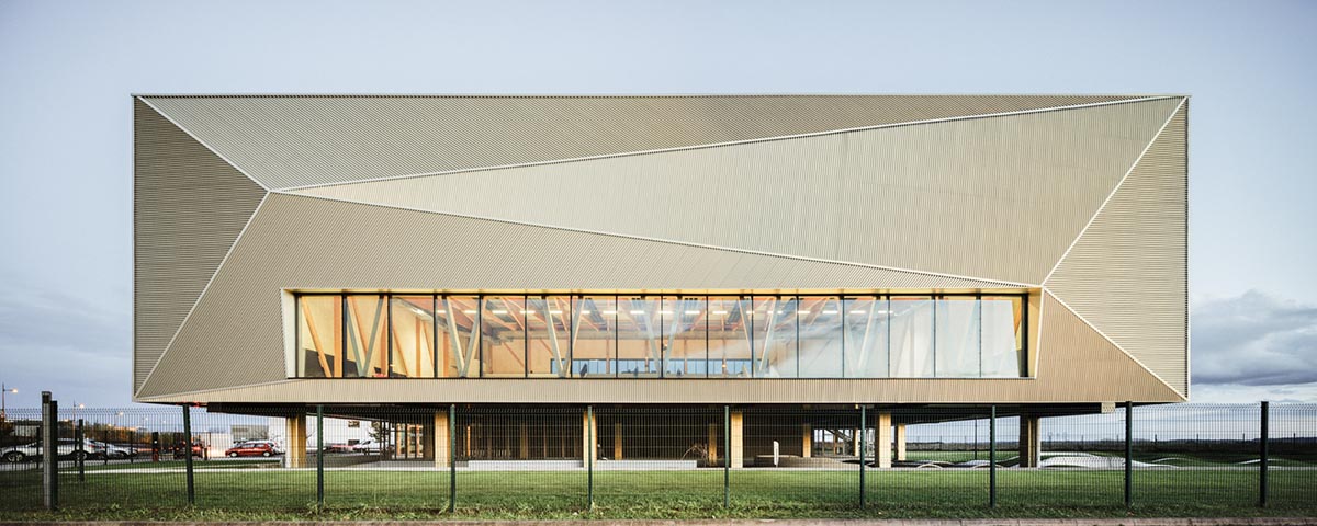 The gold-colored, folded facade gives a striking and symbolic presence to a new sports complex 