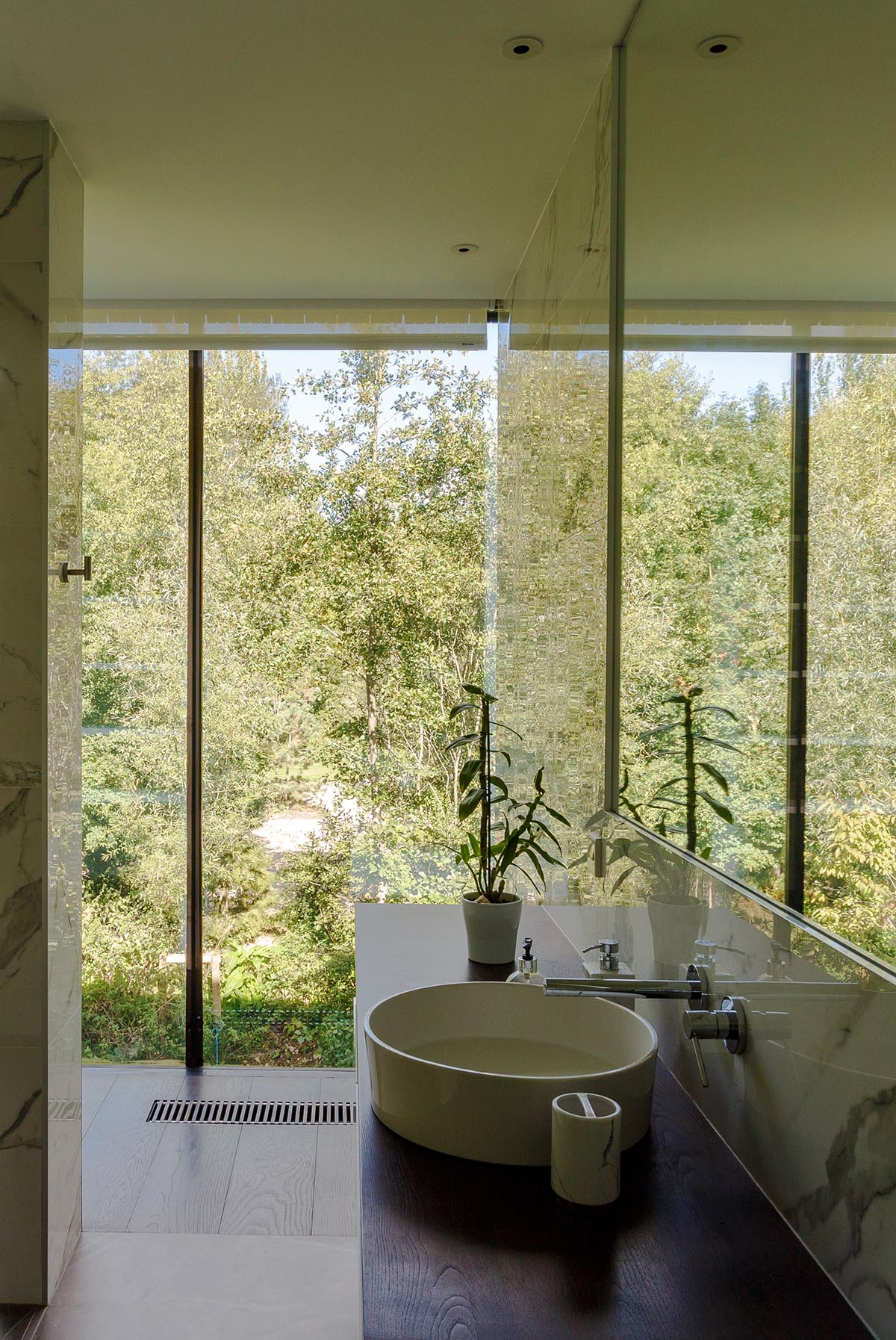 Mecanoo completes glass villa with dark stripes on a lake in Lechlade