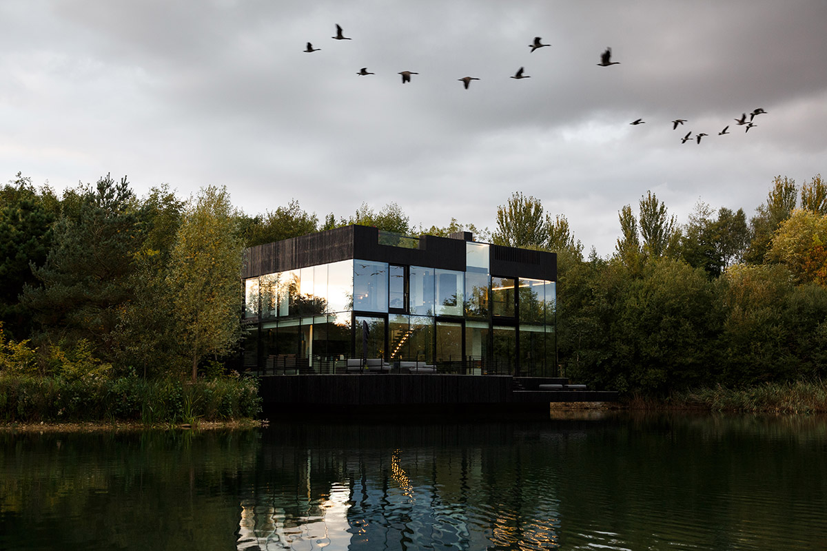 Mecanoo completes glass villa with dark stripes on a lake in Lechlade