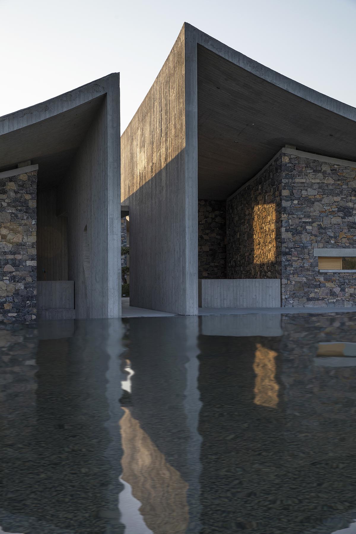 Concrete hyperboloid roofs cover masonry stone art center with a central courtyard in Shandong