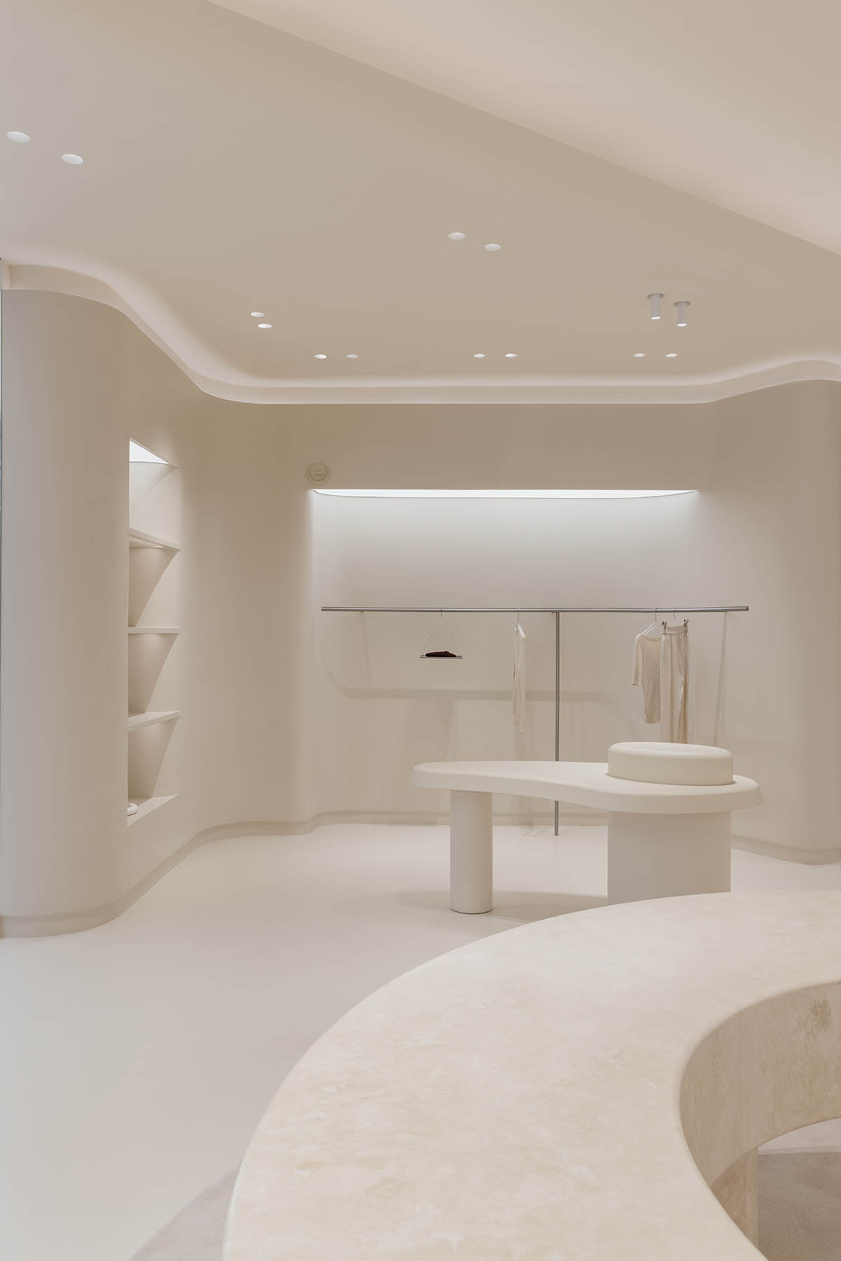 Store interiors by Sò Studio feature soft beige tones to give the feeling of