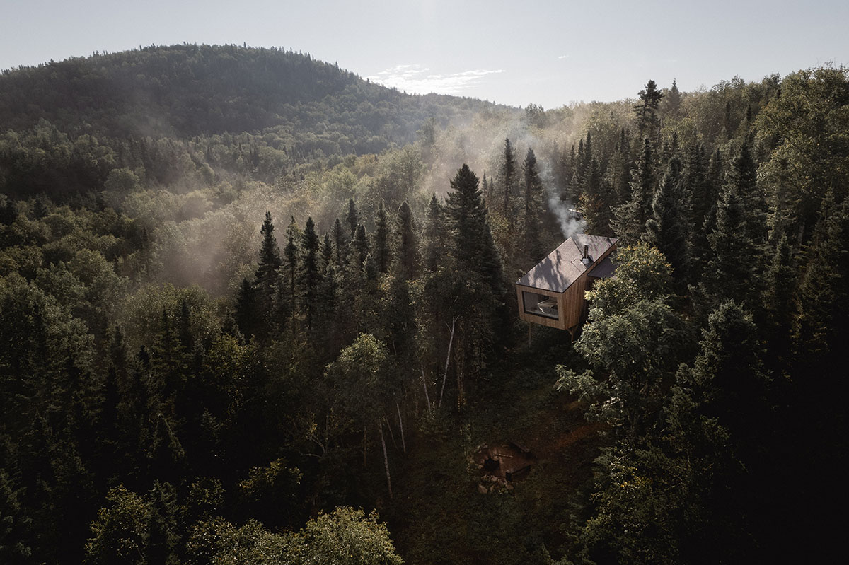 Canadian winter home designed by Atelier L'Abri looks like it is covered in  snow in the forest