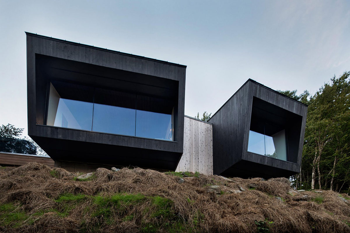 Two black wooden holiday cabins by Naturehumaine perched on a mountain of Quebec