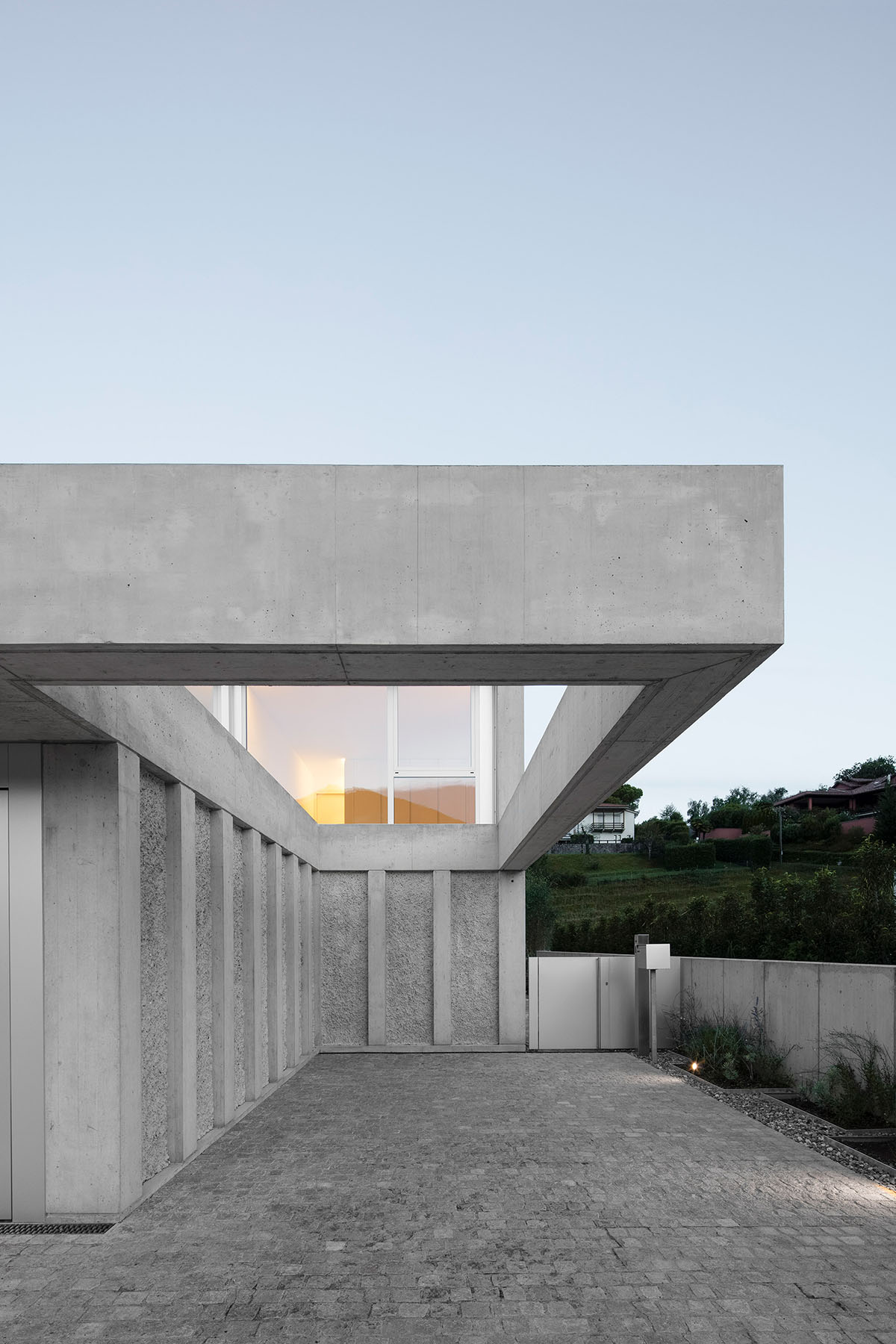 Grey concrete villa by DF_DC is characterised with trapezoidal colonnaded terrace on Comano hills