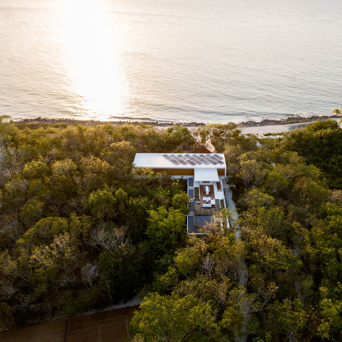 Sordo Madaleno Arquitectos' L-shaped residence disappears in a lush vegetation of Mexican island