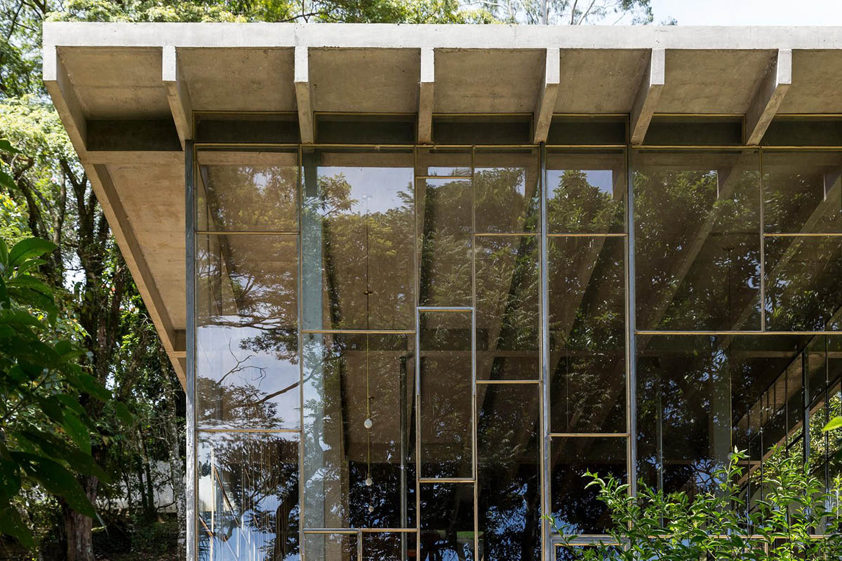 Two bold concrete platforms define this transparent library house by Atelier Branco Arquitetura
